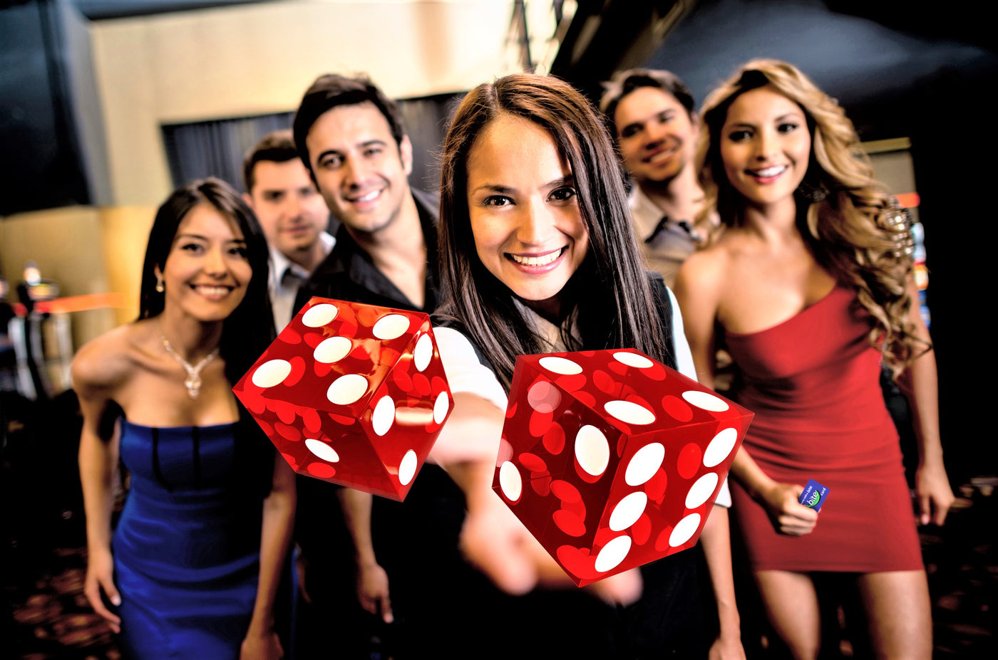 group of guys and girls smiling and having fun holding red dice and a vegas bite card