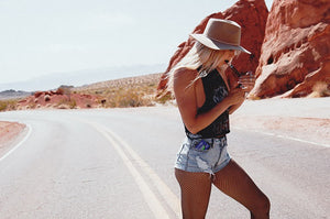 girl at red rock canyon wearing a hat and lighting a cigar