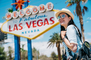 girl sightseeing at the welcome to fabulous las vegas sign smiling on a sunny day