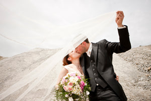 bride and groom holding and kissing each other in desert landscape